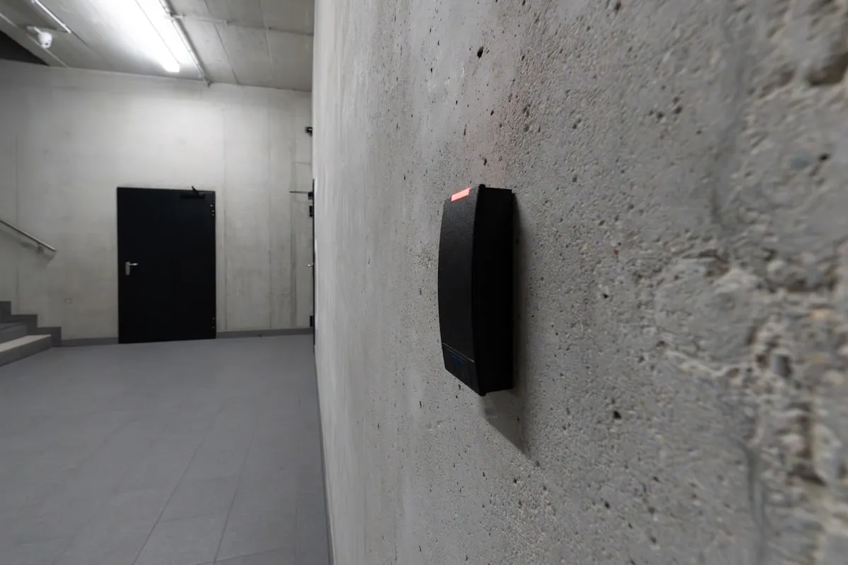 Access control card reader mounted on a concrete wall beside a door